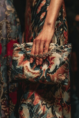 Sticker - Female hands holding a small colorful designer handbag with a pattern and a silver chain. Women's fashion and accessories