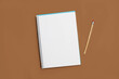 © Mercedes Fittipaldi - Cuaderno escolar sobre un fondo marrón liso y aislado. Vista superior y de cerca. Copy space. Bloc de notas en espiral sobre una mesa.