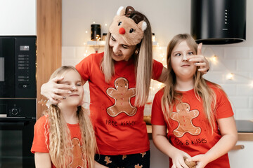 Wall Mural - A family in Christmas pajamas cooking ginger cookies in the kitchen