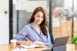© amnaj - Portrait of young Asian businesswoman sitting taking notes in the office.