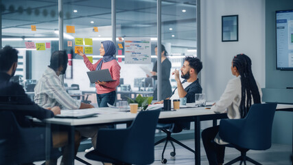 Diverse Modern Office: Motivated Muslim Businesswoman Wearing Hijab Leads Meeting, Uses Laptop, talks of Company Growth, Brainstorms with Colleagues. Digital Entrepreneurs Work on e-Commerce Project