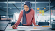 Modern Office: Motivated Muslim Businesswoman Wearing Hijab Works on Engineering Project, Does Document and Blueprints Analysis. Empowered Digital Entrepreneur Works on e-Commerce Startup Project
