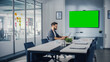 © Gorodenkoff - Office Conference Meeting Room: Handsome Hispanic Specialist Working on Laptop Computer interacts with Green Screen Choma Key Wall TV. Businessperson Working in Growing e-Commerce Startup.