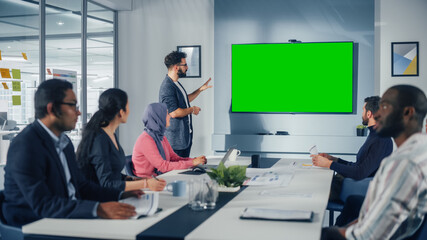 Wall Mural - Office Conference Room Meeting Presentation: Hispanic Businessman Talks, Uses Green Screen Chroma Key Wall TV. Successfully Presenting a Product to Group of Multi-Ethnic Investors. e-Commerce Strategy