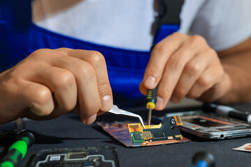 Wall Mural - Technician repairing broken smartphone at table, closeup