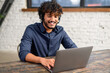 © Vadim Pastuh - Smiling ethnic Indian man wearing wireless headset using laptop for virtual connection, talking with colleagues, Indian male student involved webinar. Latin employee of customer service support