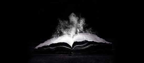 Old book. Open Bible. Antique book, on a dark background. Smoke from the book