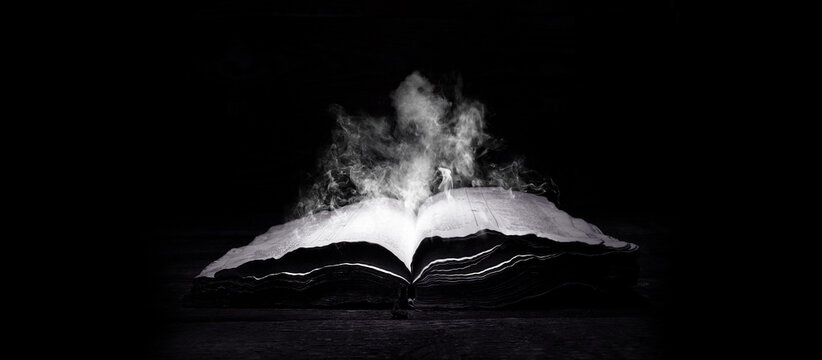 old book. open bible. antique book, on a dark background. smoke from the book