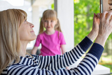 Mature Woman Hanging A Bird Feeder With Her Granddaughter