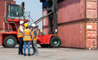 © NVB Stocker - Hispanic man harbor worker talking on the walkie-talkie radio and control loading containers at container warehouse. container yard port of import and export goods