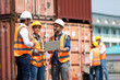 © NVB Stocker - Hispanic man harbor worker talking on the walkie-talkie radio and control loading containers at container warehouse. container yard port of import and export goods
