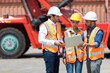 © NVB Stocker - Hispanic man harbor worker talking on the walkie-talkie radio and control loading containers at container warehouse. container yard port of import and export goods