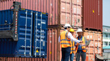 Hispanic man harbor worker talking on the walkie-talkie radio and control loading containers at container warehouse. container yard port of import and export goods