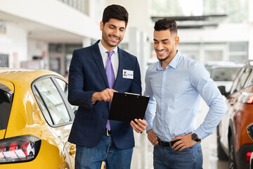 Wall Mural - Handsome arab guy having conversation with sales assistant in showroom