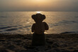 © Bojan - Teddy bear sits on the sand and watches the sunset. The sunset in Greece.