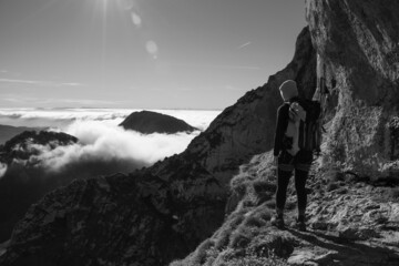 chica en la montaña con una mochila y mar de nubes de fondo