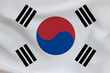 © hasbisahin - South Korea flag on waving silk background. Fabric texture.