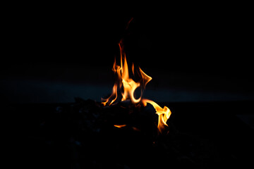 Burning wooden logs in a bonfire at night, orange flames, fire, horizontal photo,