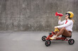 © Sunny studio - Funny businesswoman driving retro pedal car outdoor