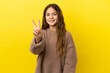 © luismolinero - Little caucasian girl isolated on yellow background smiling and showing victory sign