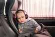 © andrei310 - Cute little girl listening to music on headphones and playing on a digital tablet in the car