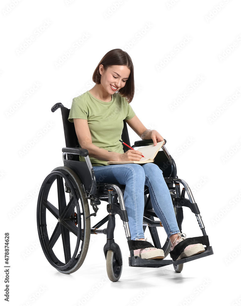 Young woman in wheelchair and with notebook on white background