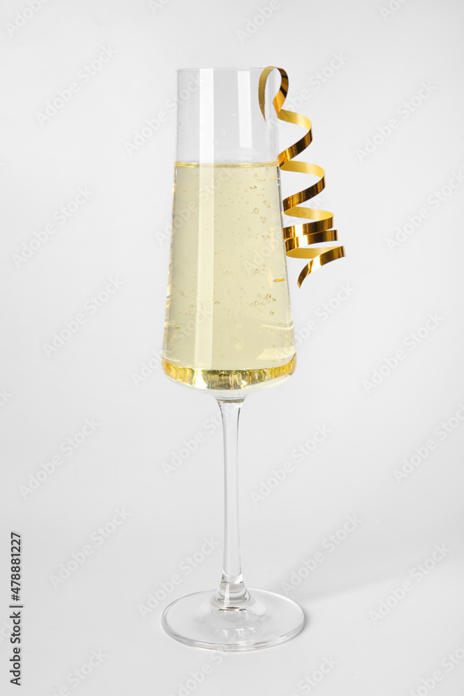 Glass of champagne with serpentine on white background