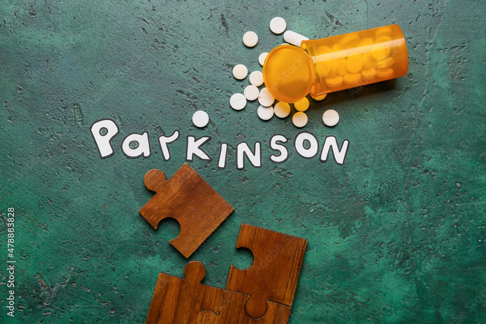 Word PARKINSON with puzzle pieces and pills on green background
