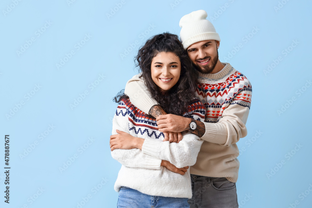 Happy young couple in warm sweaters on color background