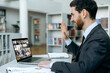 © Kateryna - Online video communication. Side view of business person communicating by video conference with group of business partners of different nationalities, using laptop while sitting in modern office