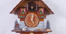 Man Adjusts Cuckoo Clock Hands Of Creative Vintage House-shaped Wall Clock With Swinging Pendulum To Cuckoo On Wall AT Home Closeup