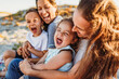 © Kelsey Smith/Stocksy - Laughing family with two moms at beach