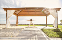 Woman Doing Yoga Pose At Luxury Hotel Spa On Beach