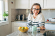 © Inti St. Clair/Stocksy - Portrait of smiling woman in her home kitchen