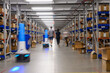 © Raymond Forbes LLC/Stocksy - Robots and workers at Ecommerce  Warehouse