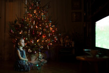 Little Girl Watching TV By A Christmas Tree