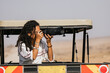© Kike Arnaiz/Stocksy - Curly woman with camera in safari car