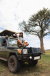 © Kike Arnaiz/Stocksy - Woman sitting on SUV in safari