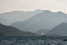 Rolling Mountains And A Sailboat Cruising