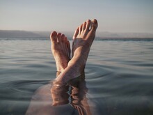 Feet Of A Holidaymaker Floating In The Dead Sea. 