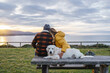 © Daniel Gonzalez/Stocksy - Anonymous dog owners resting near sea