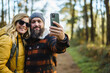 © Daniel Gonzalez/Stocksy - Couple taking selfie in autumn forest