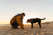 Man And Dog Playing Games At Beach During Sunset
