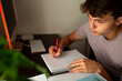 © Erin Brant/Stocksy - Close up of teen boy doing homeworkk