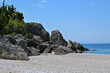 Sandy beach by the sea near Saranda with rocks and trees under a blue sky in Albania