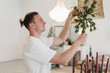 © Alina Hvostikova/Stocksy - Man decorating lamp with fir branches