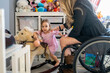 © Santi Nuñez/Stocksy - Mother in wheelchair with her daughter.