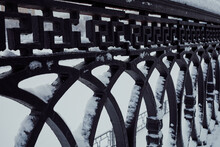Ornamental Wrought Iron Fence With Curve Parts In Snow. Close Up View Of Steel Decorative Fencing In Winter Time
