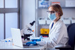 canvas print picture Female Lab Worker Wearing Lab Coat Analysing Samples In Laboratory With Laptop And Microscope