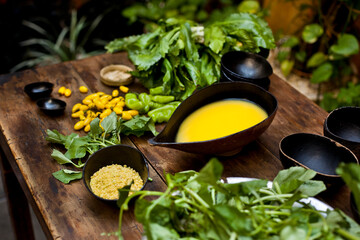 Amazonian cuisine. Green ingredients, manioc soup on a wooden table set.